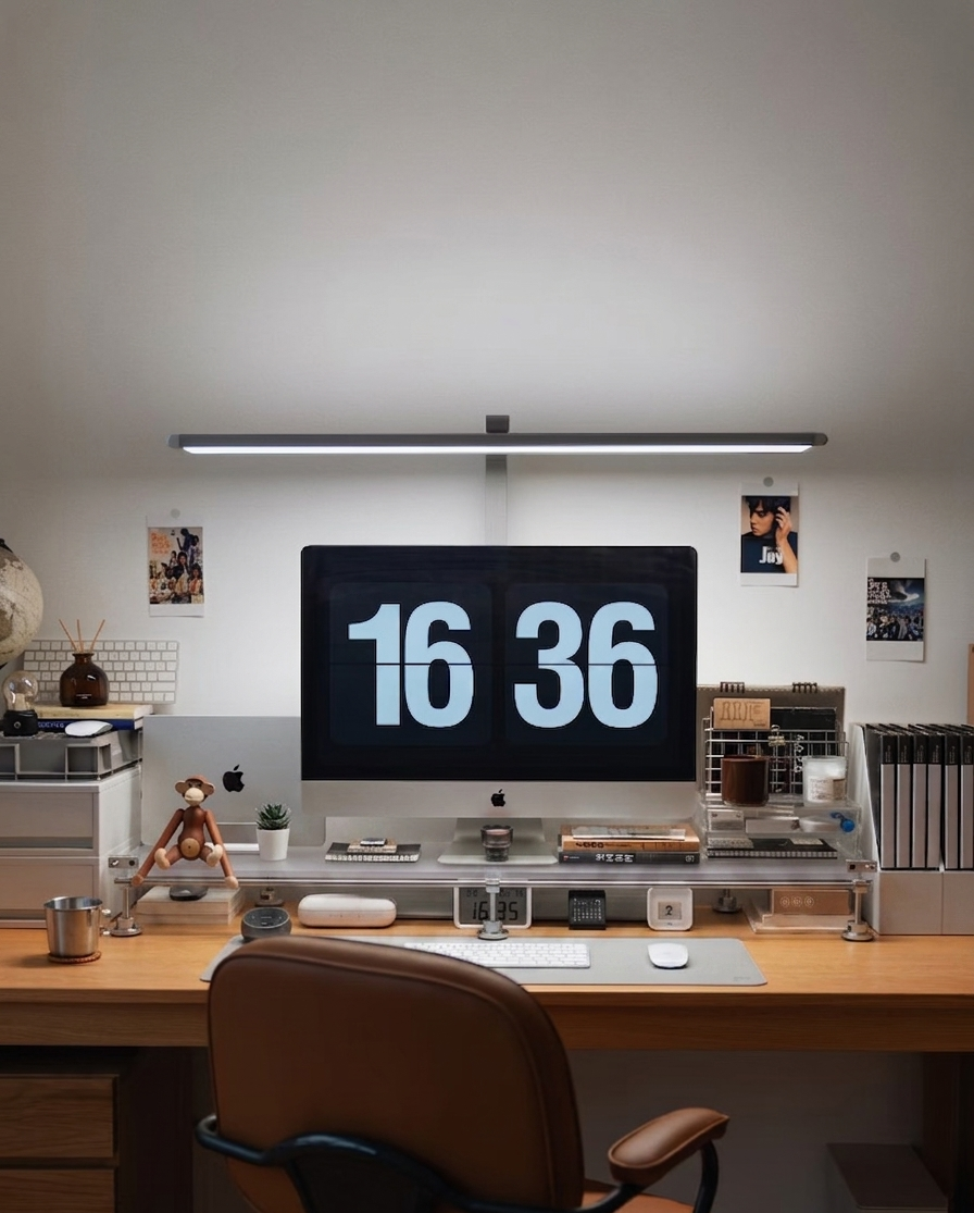 HushLume chrome plated carbon steel and acrylic desk shelf organizer under an iMac and monitor desk lamp in a cozy workspace setup.