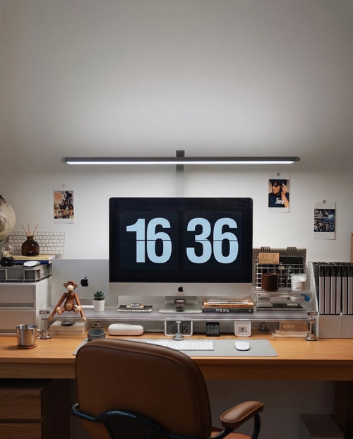 HushLume chrome plated carbon steel and acrylic desk shelf organizer under an iMac and monitor desk lamp in a cozy workspace setup.