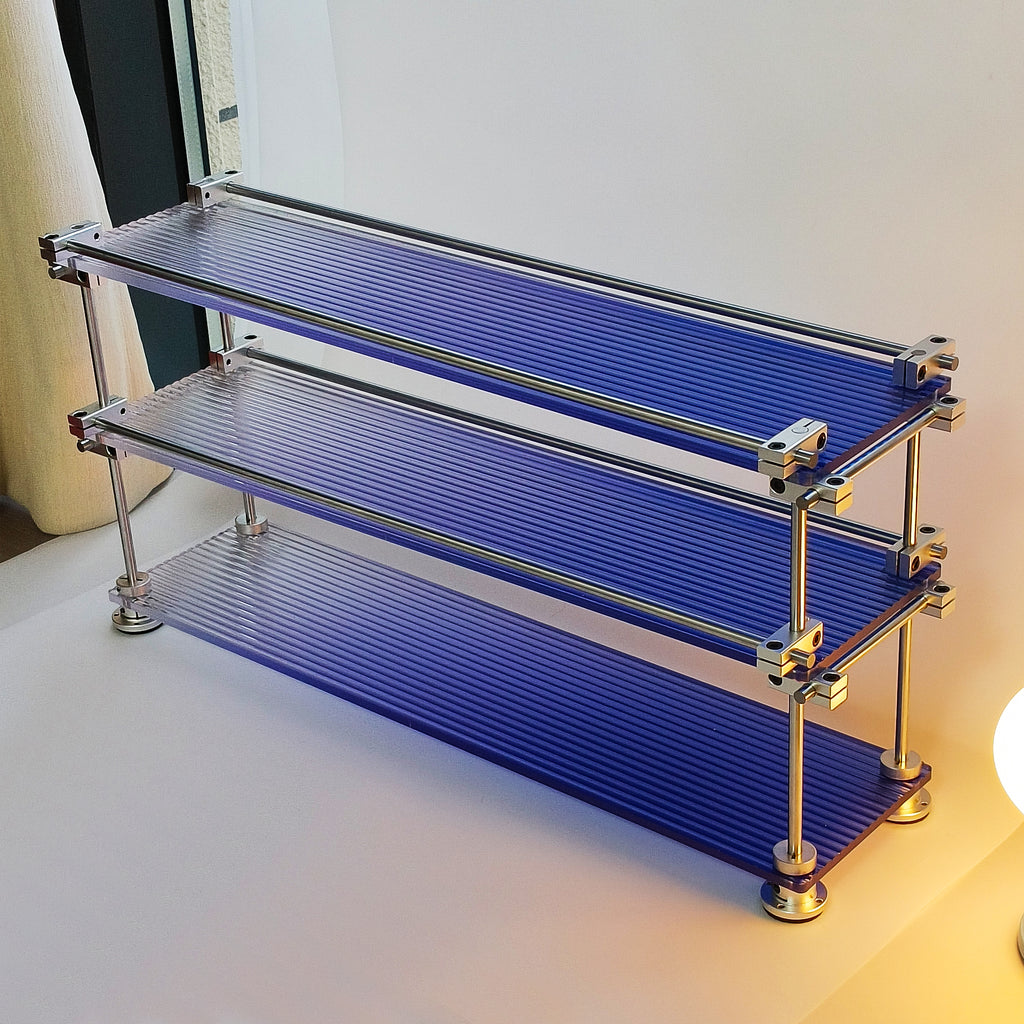 Eye-level shot of HushLume 3-tier chrome steel linear shaft storage shelf with fluted blue acrylic panels, highlighting space-saving desktop organization.