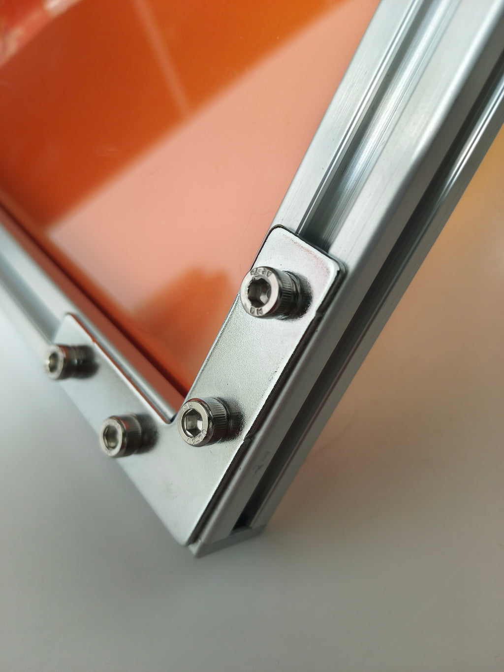 Close-up detail of HushLume industrial aluminum picture frame with customizable translucent orange acrylic backing panel and heavy-duty hardware.