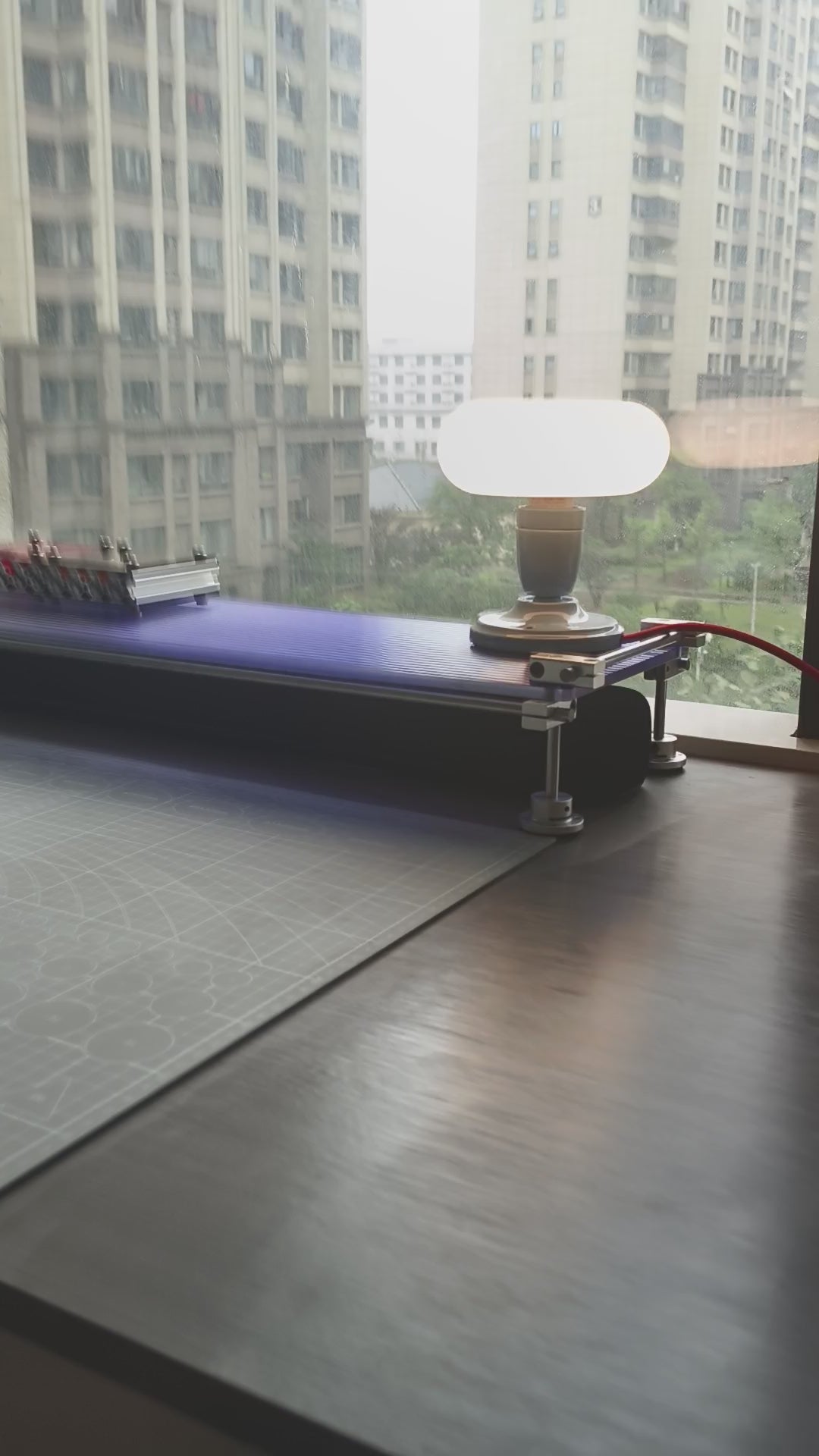 Video showcasing the translucent blue acrylic panel and chrome plated linear shaft desk shelf under natural light with a desktop lamp.