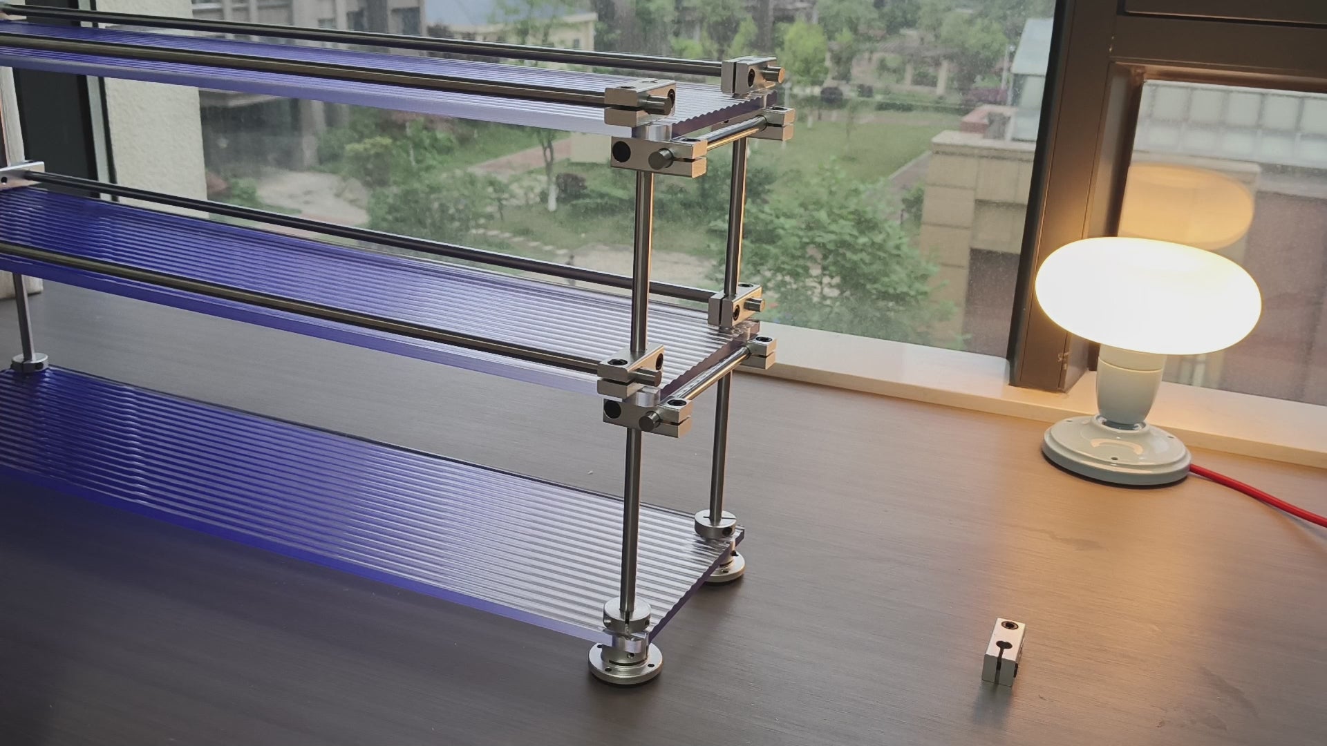 Video showcasing the details of HushLume 3-tier chrome steel linear shaft storage shelf with fluted blue acrylic panels on a desk.